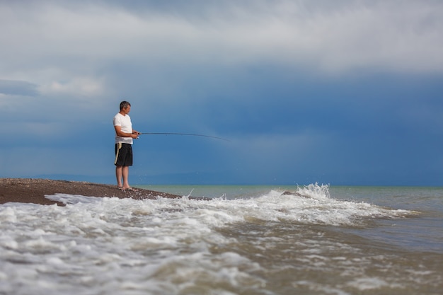 Fisherman with a fishing rod on the beach