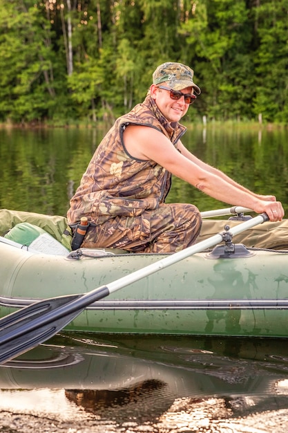 Fisherman with fishing rods is fishing in a rubber boat on lake or river