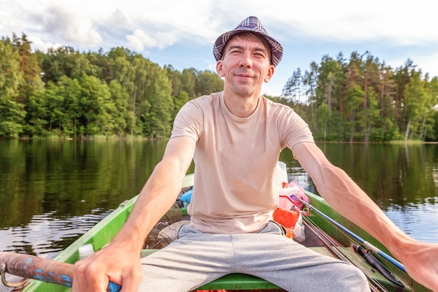 Fisherman with fishing rods is fishing in a rubber boat on lake or river