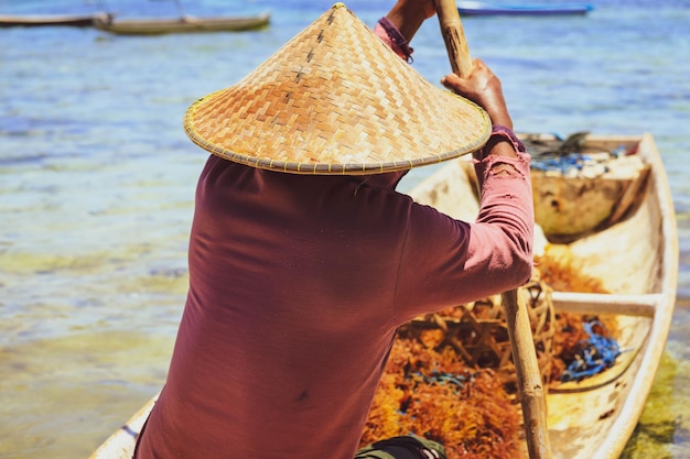 Fisherman on wooden boat with seaweed on boat going to work on the sea