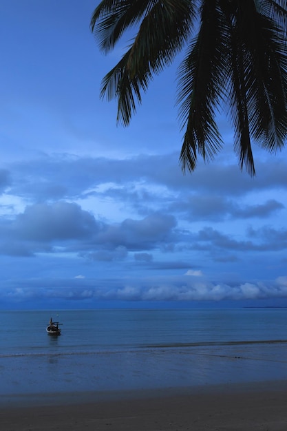 Fishing boat floating in calm sea near sandy beach