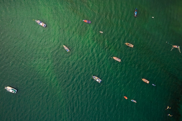 Fishing boat and long tail boat on the green sea aerial view 