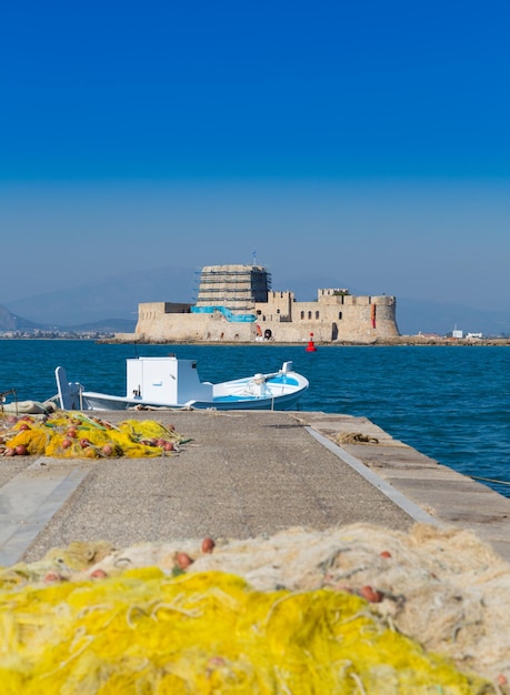 Fishing boat and nets with Bourtzi castle in background Nafplio Greece