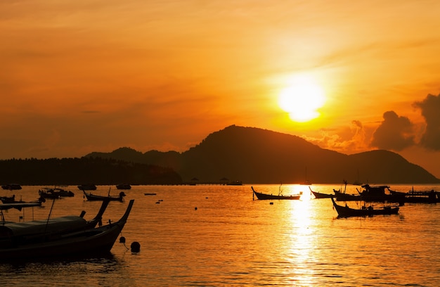 Fishing boat in the sea in morning time with beautiful sunrise and reflection in the water