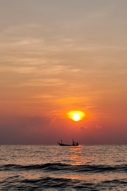 The fishing boat in the sea with a sunrise background in a vertical frame