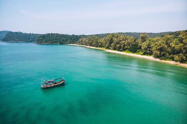 Fishing boats are sailing in the sea to catch fish. The fishing boat is a boat made up of wood and a small fishing boat. There is a background image of the island and the blue sea.