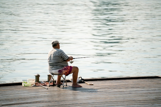 A fishing hobby, male fisherman sitting on the city river embankment and catching fish