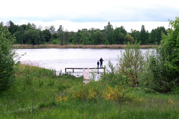 Fishing is the best outdoor recreation for the whole family a man and a child stand on a bridge in the middle of a lake and fish with a fishing rod