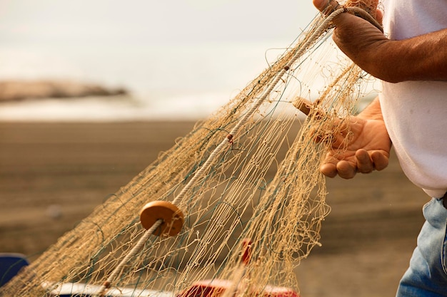 fishing net in the hands of a fisherman, preparing gear to go out to sea, in the background the Medi