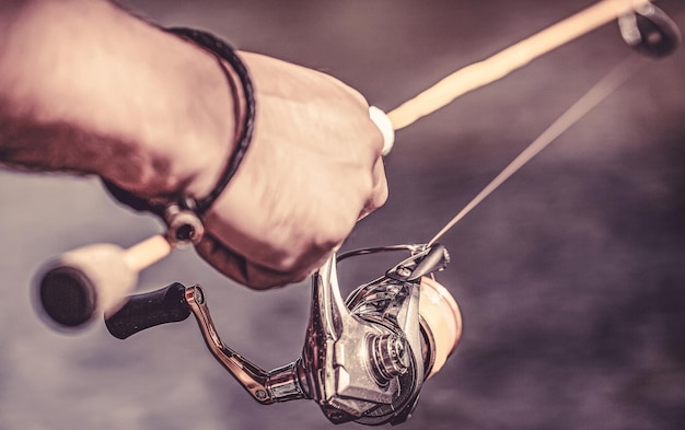 Fishing Reel Fishing Rod with Aluminum Body Spool Fishing Gear Fish Supplies and Equipment Fishing reel closeup on the background of the river