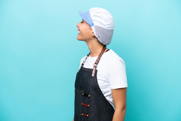 Fishwife Argentinian woman isolated on blue background laughing in lateral position