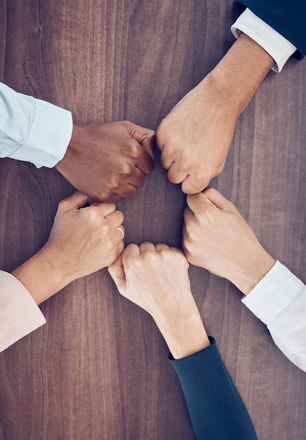 Fist above and employees meeting with support partnership and solidarity together at work Hands of corporate diversity and motivation from workers in a team for business and goal on a table