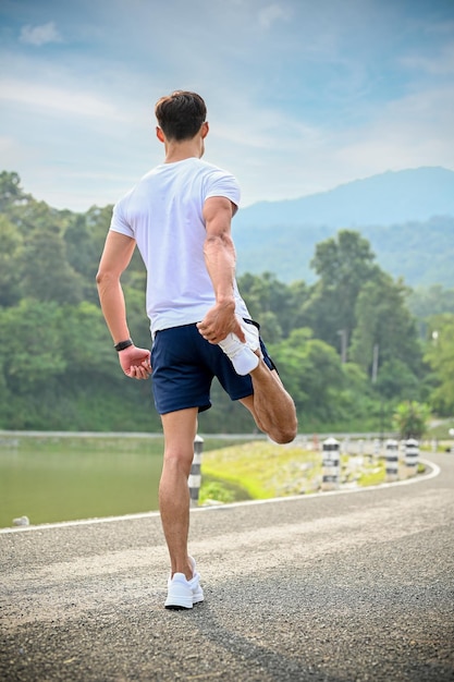 Fit and active Asian athletic man stretching his leg warmup before running