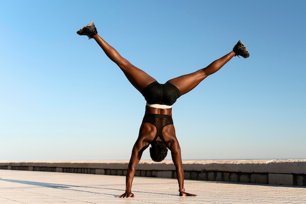 Fit athletic female doing hand standing on beach