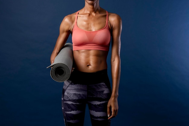 Fit black woman holding a yoga mat