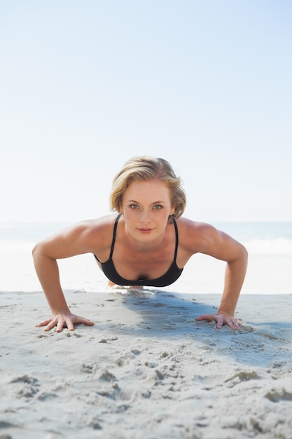 Fit blonde in plank position on the beach