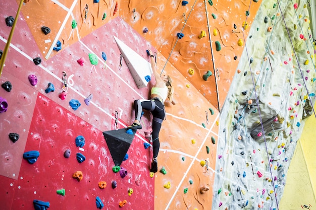 Fit blonde rock climbing indoors