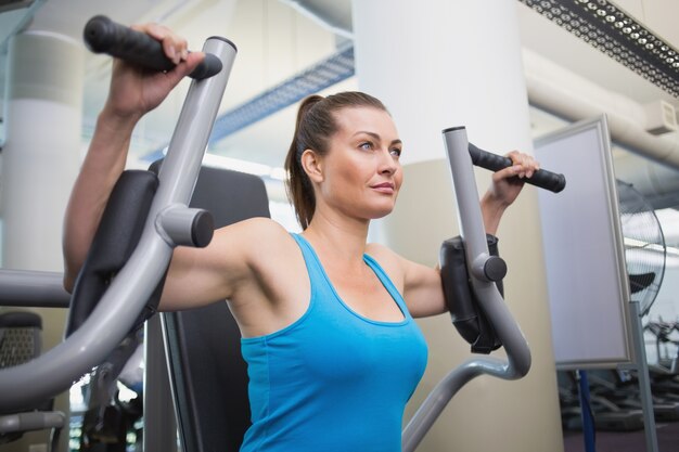 Fit brunette using weights machine for arms