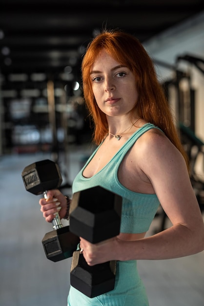 Fit caucasian woman working out with dumbbells at the gym Fitness muscular body