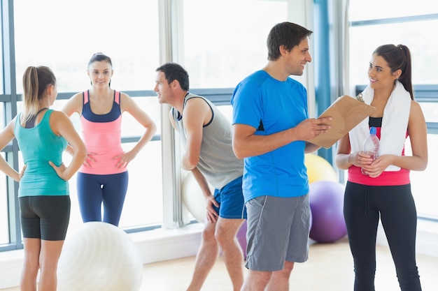 Fit couple with friends in background in exercise room