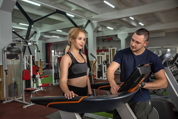 Fit female client running on treadmill with her personal trainer in a sport centre sportive lifestyle