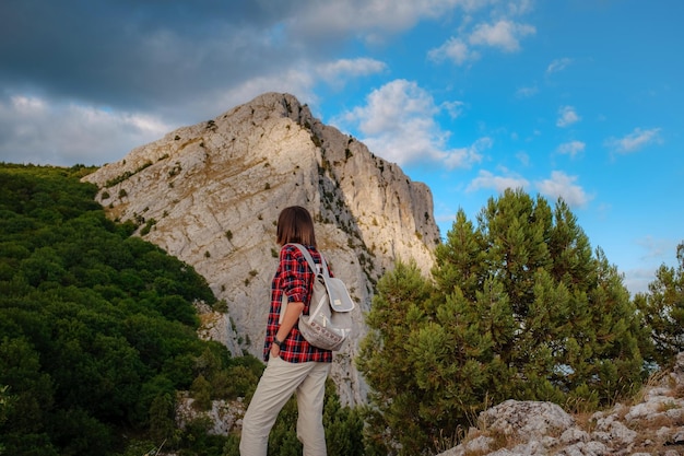 Fit female hiker with backpack standing on a rocky mountain ridge