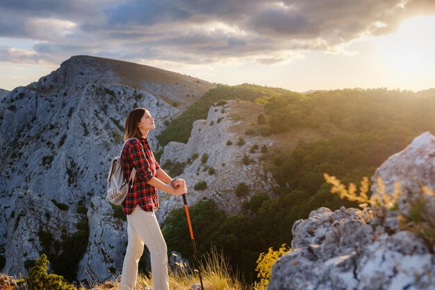 Fit female hiker with backpack standing on a rocky mountain ridge