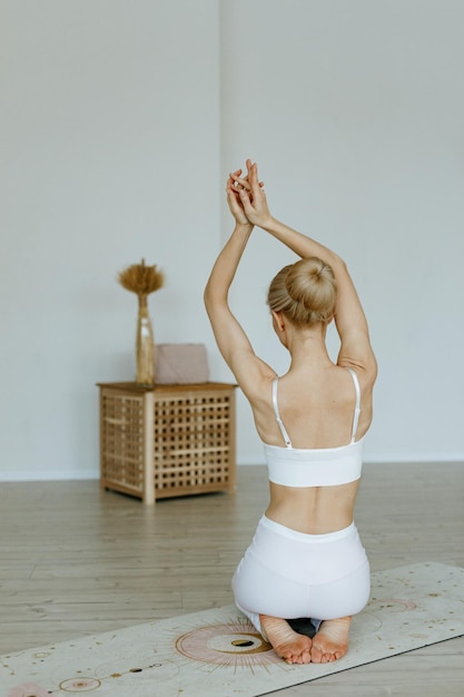 A fit female instructor trains on a yoga mat in a bright studio