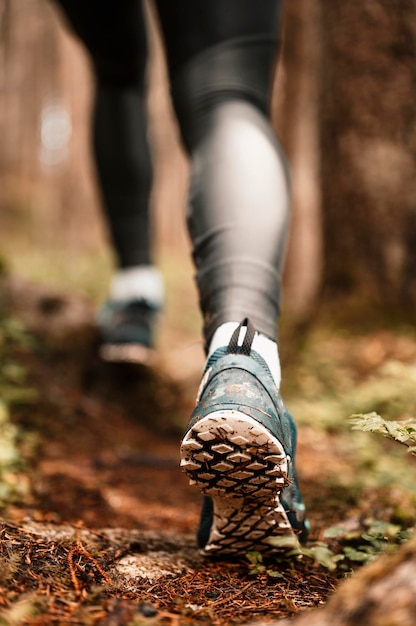 Fit female jogger training for cross country forest trail race in nature park Detail of running trail shoes