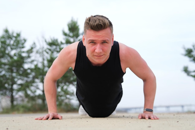 fit fitness man athlete athletic guy doing push ups workout exercise on ground training outdoors