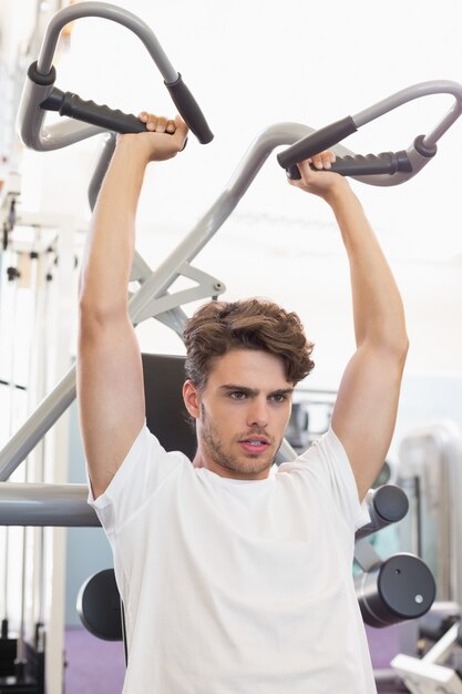 Fit focused man using weights machine for arms 