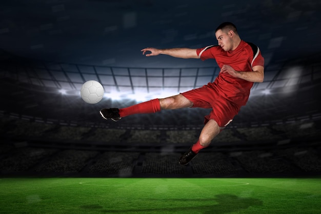 Fit football player playing and kicking against large football stadium with fans in yellow