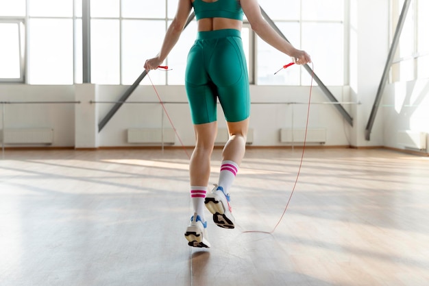 Fit girl jumping rope in gym selective focus on buttocks Workout concept fit body