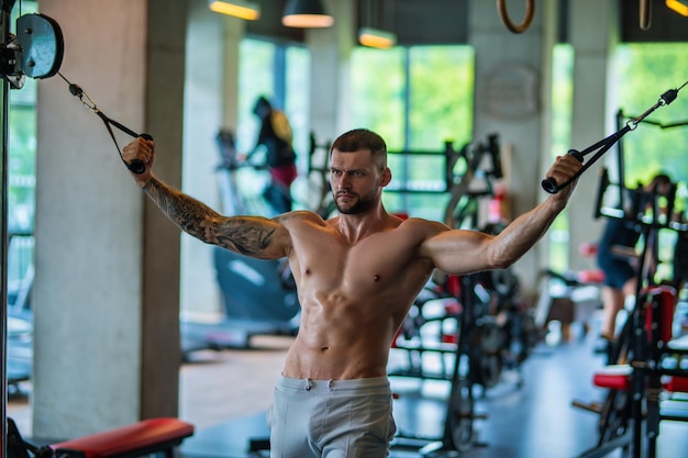 Fit guy doing exercise at gym handsome sporty man workout with with dumbbells on gym male athlete wi