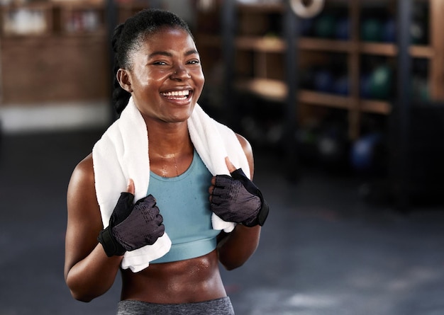 Fit and happy Shot of a sporty young woman posing with a towel around her neck at gym