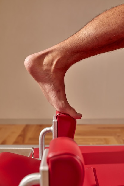 Fit man doing a lunge stretch yoga pilates exercise to strengthen and tone his muscles using a reformer in a gym