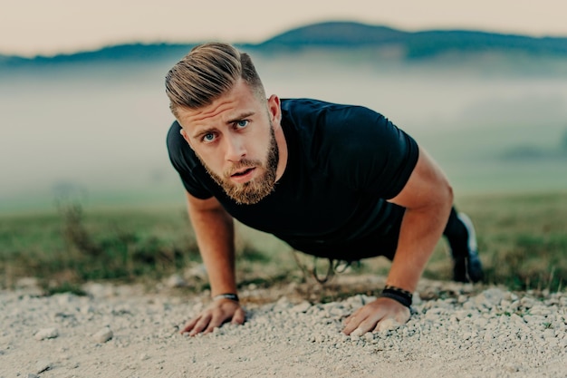 Fit man doing push ups exercise at outdoor gym. Core body workout athlete planking or doing pushup on grass.