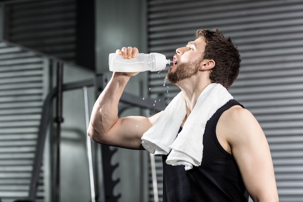 Fit man drinking water at crossfit gym