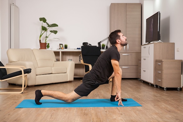 Fit man in his 30s doing yoga on a mattress in his house. Healthy sport lifestyle