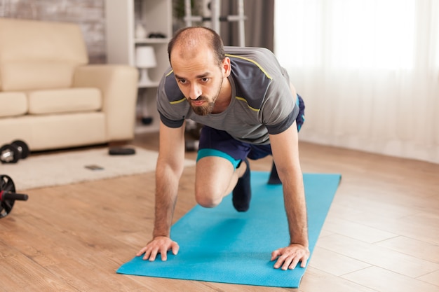 Fit man working his body on yoga mat during self isolation.