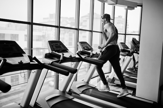 Fit and muscular arabian man running on treadmill in gym.