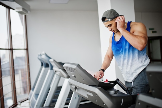 Fit and muscular arabian man running on treadmill in gym