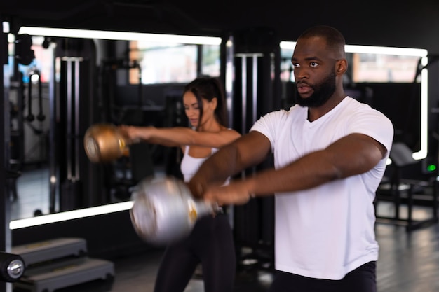 Fit and muscular couple focused on lifting a dumbbell during an exercise class in a gym