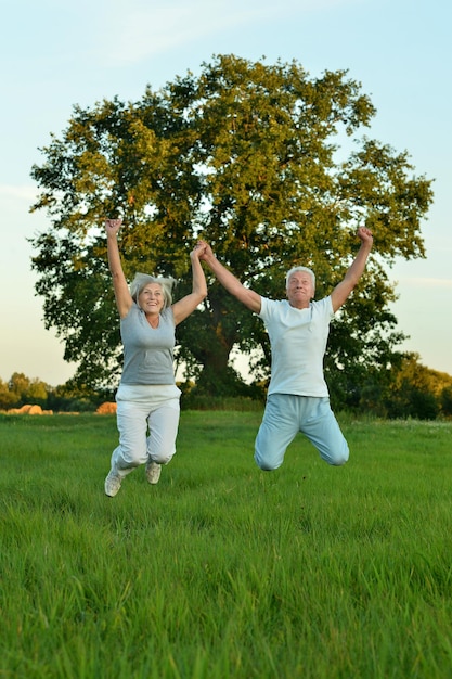 Fit senior couple jumping in park