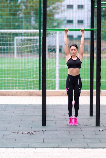 Fit sporty young woman exercising on a bar