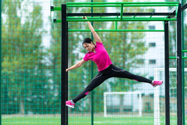 Fit sporty young woman working out on parallel bar