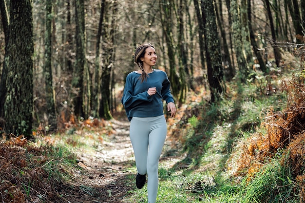 Photo fit woman in activewear running along trail in green forest