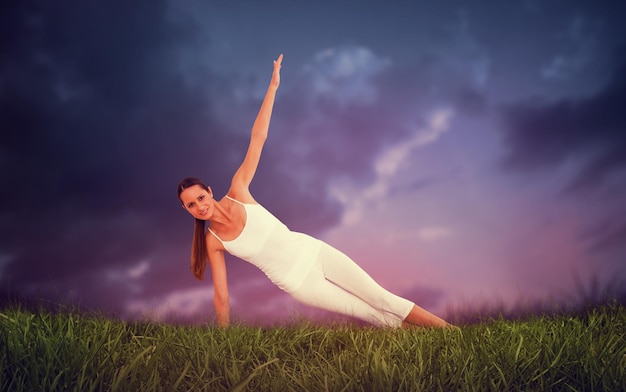 Fit woman doing pilate exercises in the fitness studio against blue sky over grass