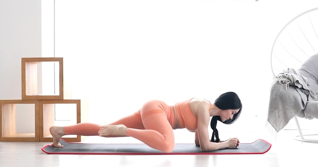 Fit woman doing plank exercise, workout at home.