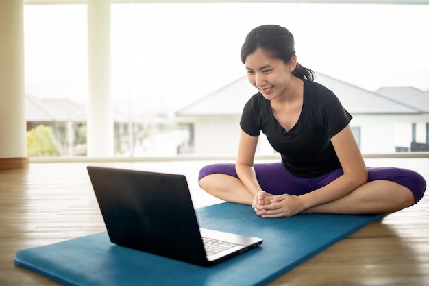 Fit woman doing yoga and watching online tutorials on notebook